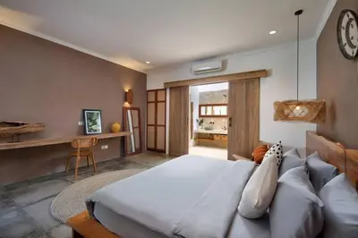 a bedroom with a bed and a desk with a clock at Villa Pawikan Gorgeous 4 beds villa in the heart of Seminyak in Seminyak