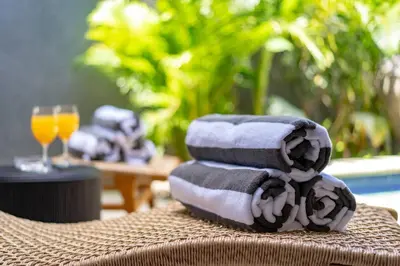 a stack of towels on a table with a glass of orange juice at Central 3bd Modern Villa with Private Pool and Play Area in Kerobokan