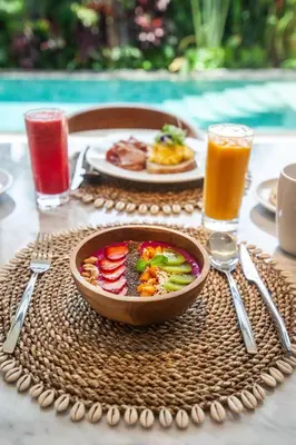 a table with a bowl of food and a plate of juice at Luxury 3bd Villa 5 Min From Berawa Beach in Canggu