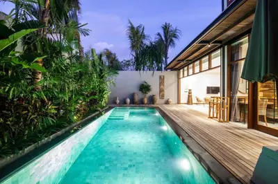 an infinity pool in a house with a wooden deck at Luxury 3bd Villa 5 Min From Berawa Beach in Canggu