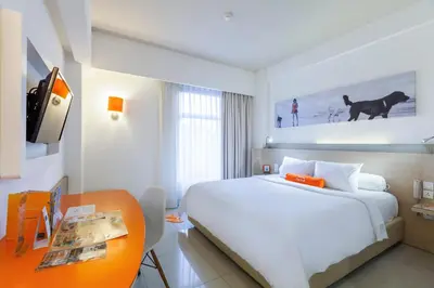 a bedroom with a large white bed and a desk at HARRIS Hotel Seminyak in Seminyak