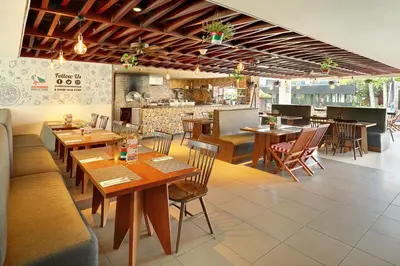 a restaurant with wooden tables and chairs and a counter at HARRIS Hotel Seminyak in Seminyak