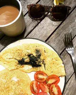 a plate of food with tomatoes and a cup of coffee at Sugiras Living in Denpasar