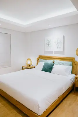 a bedroom with a large white bed with a wooden headboard at Casa Amarta Canggu - Boutique Lofts & Detox SPA in Canggu