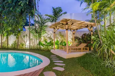 a backyard with a pool and a wooden umbrella and a chair at Villa Alamanda Livia Seminyak Design spacious 2bdr and private pool in Seminyak
