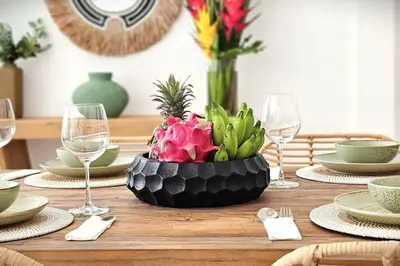a wooden table with a centerpiece of flowers and wine glasses at Villa Alamanda Livia Seminyak Design spacious 2bdr and private pool in Seminyak