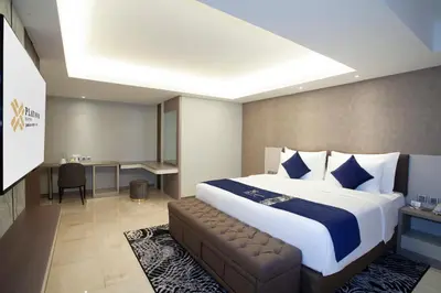 a hotel room with a large bed and a couch at Platinum Hotel Jimbaran Beach Bali in Jimbaran