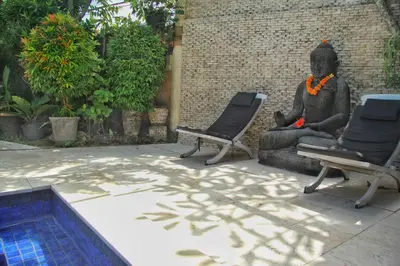 a statue sitting next to two chairs next to a pool at Villa Yauda - Charming 3BR w/Private pool & Garden in Seminyak