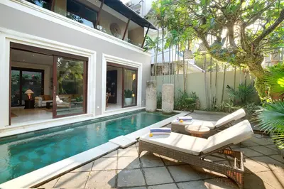 a villa with a swimming pool with a patio furniture and a house at Villa Giva Seminyak - 2 Bedrooms Seminyak in Seminyak