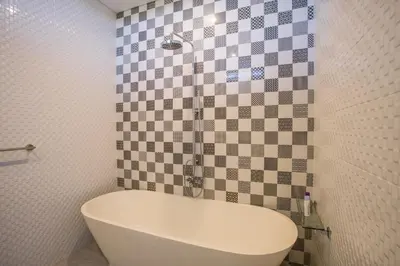 a white tub in a bathroom with checkered tiles at Berawa Bali Beach Villas Canggu in Canggu