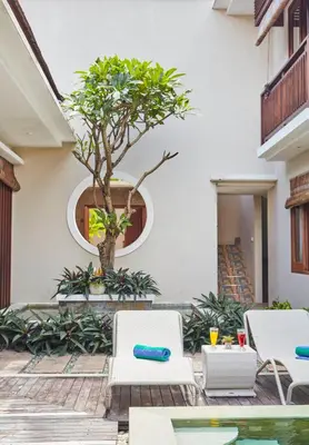 a courtyard with two chairs and a tree at Dreamscape Bali Villas Canggu in Canggu