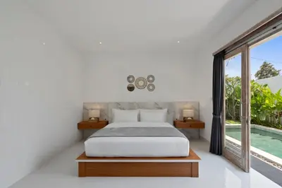 a bedroom with a bed and a large window at Serenity Villa by Betterplace in Kerobokan