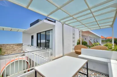 a balcony with a white table and chairs at Sayang Villa Bali in Kerobokan