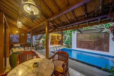a patio with a table and chairs and a swimming pool at Villa Arumanis in Canggu