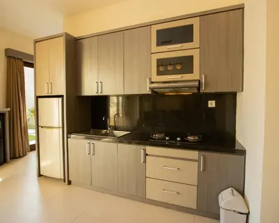 a kitchen with wooden cabinets and a microwave and a refrigerator at Luxotic Private Villa and Resort in Nusa Dua