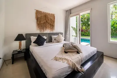 a bedroom with a large bed and a pool at Villa Khanphi Seminyak in Seminyak