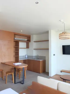 a living room with a table and a kitchen at The Fields Hotel and Apartment in Seminyak