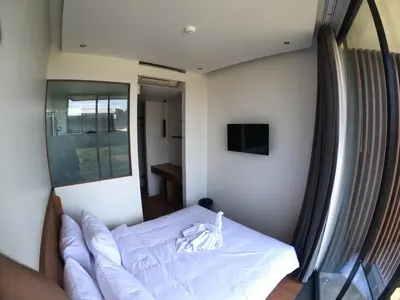 a bedroom with a bed with white sheets and a mirror at The Fields Hotel and Apartment in Seminyak