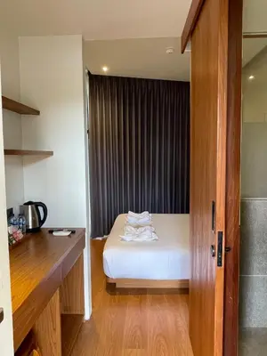 a small bedroom with a bed and a window at The Fields Hotel and Apartment in Seminyak