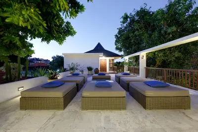 a patio with blue cushioned furniture on a deck at Villa Amira 5BR Villa 17m Pool Near Legian Beach in Legian