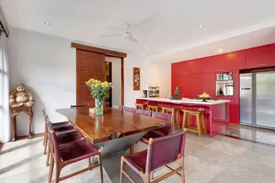 a kitchen with a wooden table and red cabinets at Villa Amira 5BR Villa 17m Pool Near Legian Beach in Legian
