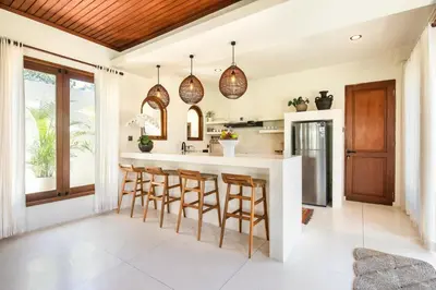 a kitchen with a island with bar stools at Colonial-style 4BR Villa, 400m to Canggu Beach in Canggu