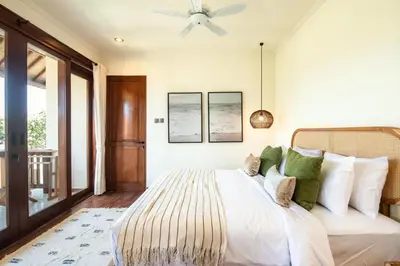 a bedroom with a bed and a ceiling fan at Colonial-style 4BR Villa, 400m to Canggu Beach in Canggu