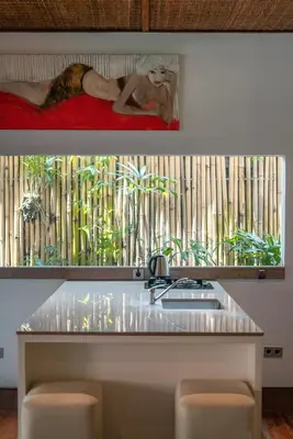 a woman sitting on a bed in front of a window at Villa Claudia - Chic 3BR Family Villa with Pool & Play near Seminyak in Kerobokan