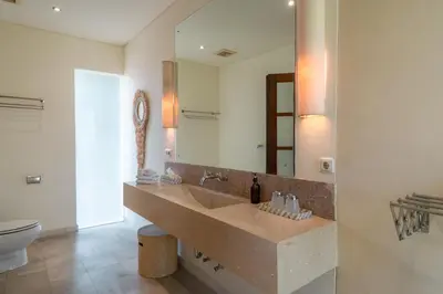 a bathroom with a sink and a toilet and a mirror at Villa Claudia - Chic 3BR Family Villa with Pool & Play near Seminyak in Kerobokan