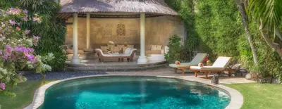 a swimming pool in a yard with chairs and a house at Villa Kubu Seminyak in Seminyak