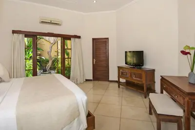 a bedroom with a bed and a flat screen tv at Villa Kubu Seminyak in Seminyak
