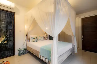 a bedroom with a canopy bed with white curtains at Villa Jami by BaliSuperHost in Seminyak