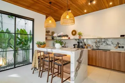 a kitchen with a bar with stools at Villa Anita Umalas by Santi Management in Kerobokan