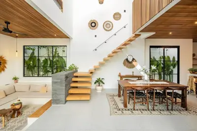 a living room with a wooden table and a staircase at Villa Anita Umalas by Santi Management in Kerobokan