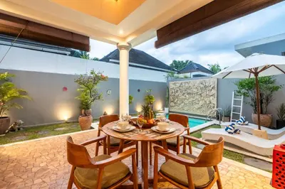 a patio with a table and chairs and a pool at Villa Vaiana Seminyak in Seminyak
