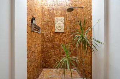 a bathroom with a stone shower with a face on the wall at Villa Vaiana Seminyak in Seminyak