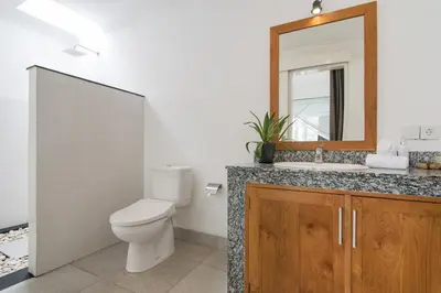 a bathroom with a toilet and a sink and a mirror at Stylish Three Bedroom Villa Near Atlas Beach Club & Beach. in Canggu