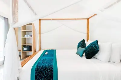 a bedroom with a white bed with blue pillows at Stylish Three Bedroom Villa Near Atlas Beach Club & Beach. in Canggu