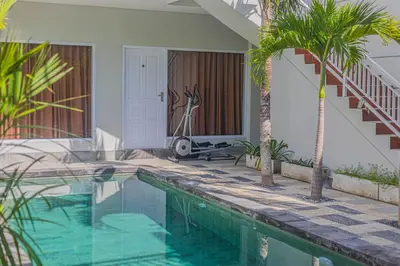 a swimming pool in front of a house with palm trees at Villa Rose 1 Sanur in Sanur