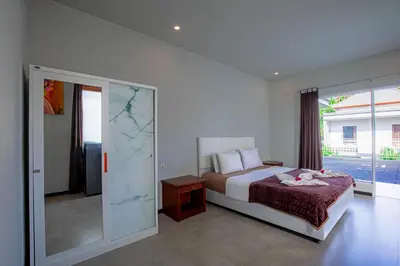 a bedroom with a bed and a sliding glass door at Villa Rose 1 Sanur in Sanur