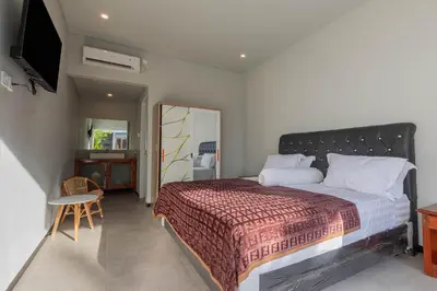 a bedroom with a bed and a table and a mirror at Villa Rose 1 Sanur in Sanur