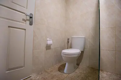a bathroom with a toilet and a glass door at Villa Rose 1 Sanur in Sanur