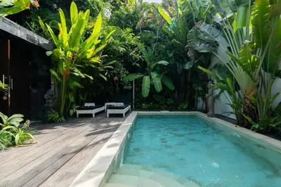 a swimming pool in the middle of a garden at The Gardens Seminyak in Seminyak
