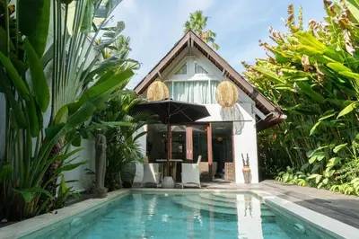 a villa with a swimming pool in front of a house at The Gardens Seminyak in Seminyak