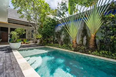a swimming pool in a garden with palm trees at Villa Celine 2 chambres piscine Seminyak BALI in Seminyak
