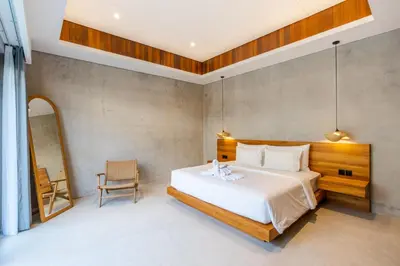 a bedroom with a large white bed and a chair at J4 Villas Sanur in Sanur