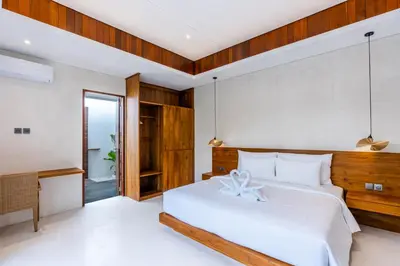 a bedroom with a white bed with a wooden headboard at J4 Villas Sanur in Sanur