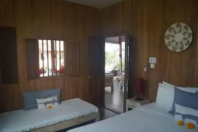 two beds in a room with wood paneling at Villa Joglo Oberoi Seminyak Beautiful 4BR Villa Prime Location in Seminyak