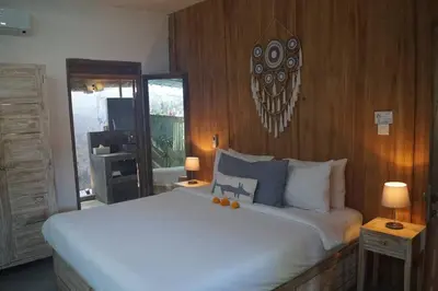 a bedroom with a large white bed with wooden walls at Villa Joglo Oberoi Seminyak Beautiful 4BR Villa Prime Location in Seminyak