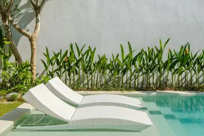 a white lounge chair next to a swimming pool at Villa Marina Seminyak in Seminyak